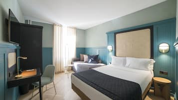 Una habitación de hotel con una cama grande, un escritorio, una silla y un televisor.