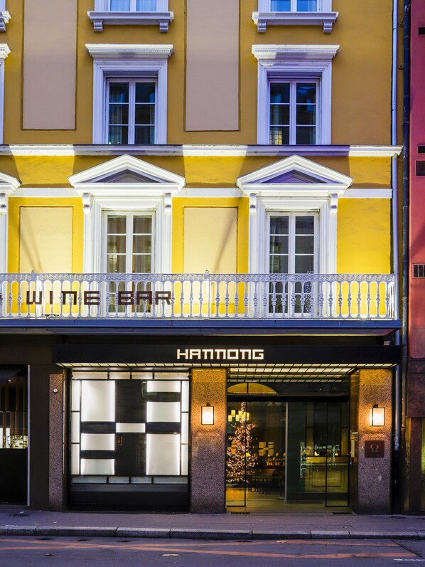 A hotel facade with a yellow and white color scheme, a balcony with railing, and the name 'HANNONG' displayed.