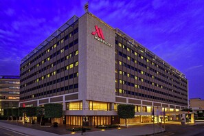 A multi-story Marriott hotel with a prominent logo, large windows, and a well-lit entrance area.