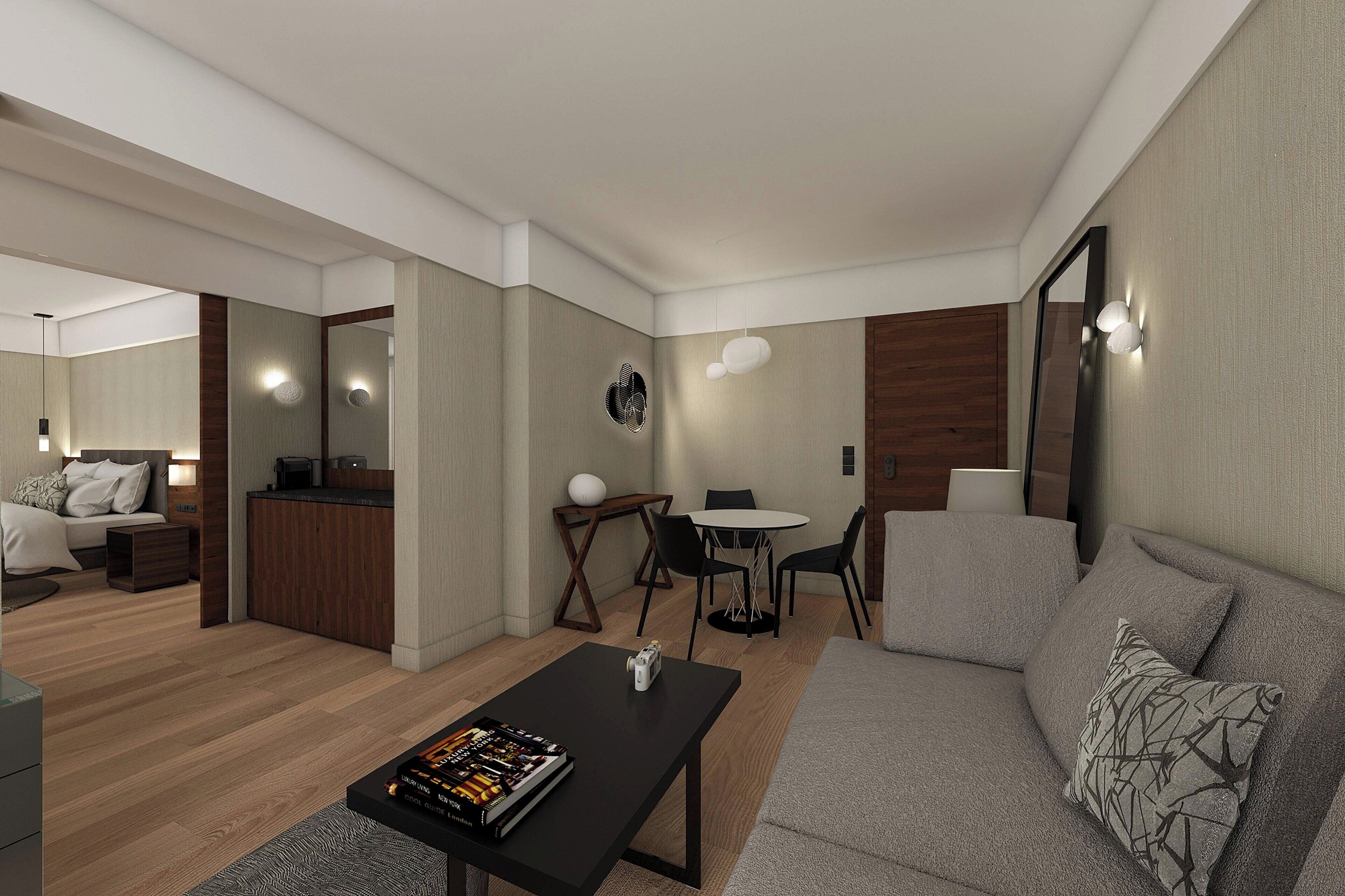 A modern living room with a sofa, a coffee table, a dining table with chairs, a kitchen area, and a large mirror.