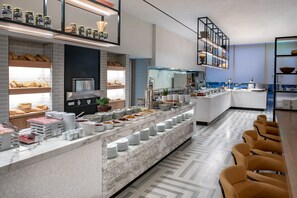 A modern breakfast bar with a variety of food items and a seating area with chairs.