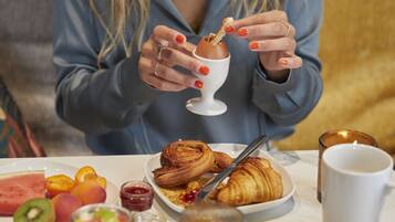 A breakfast table with various dishes including croissants, fruits, and a glass of juice.