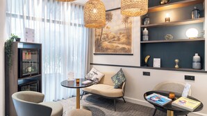 Quarto moderno com sofá, duas poltronas, uma mesinha e uma estante.