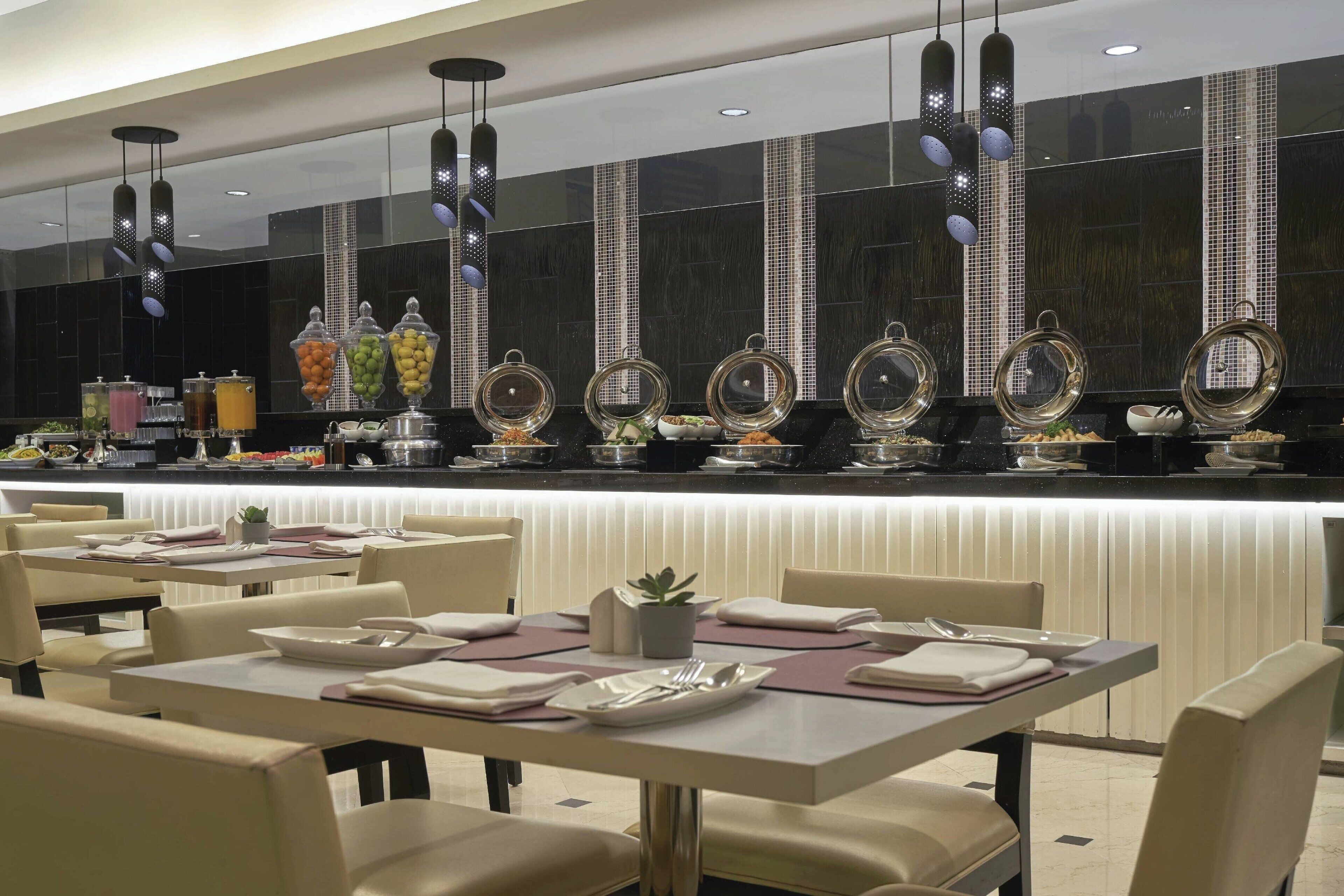 A restaurant with a buffet area featuring various food items and a modern interior design.