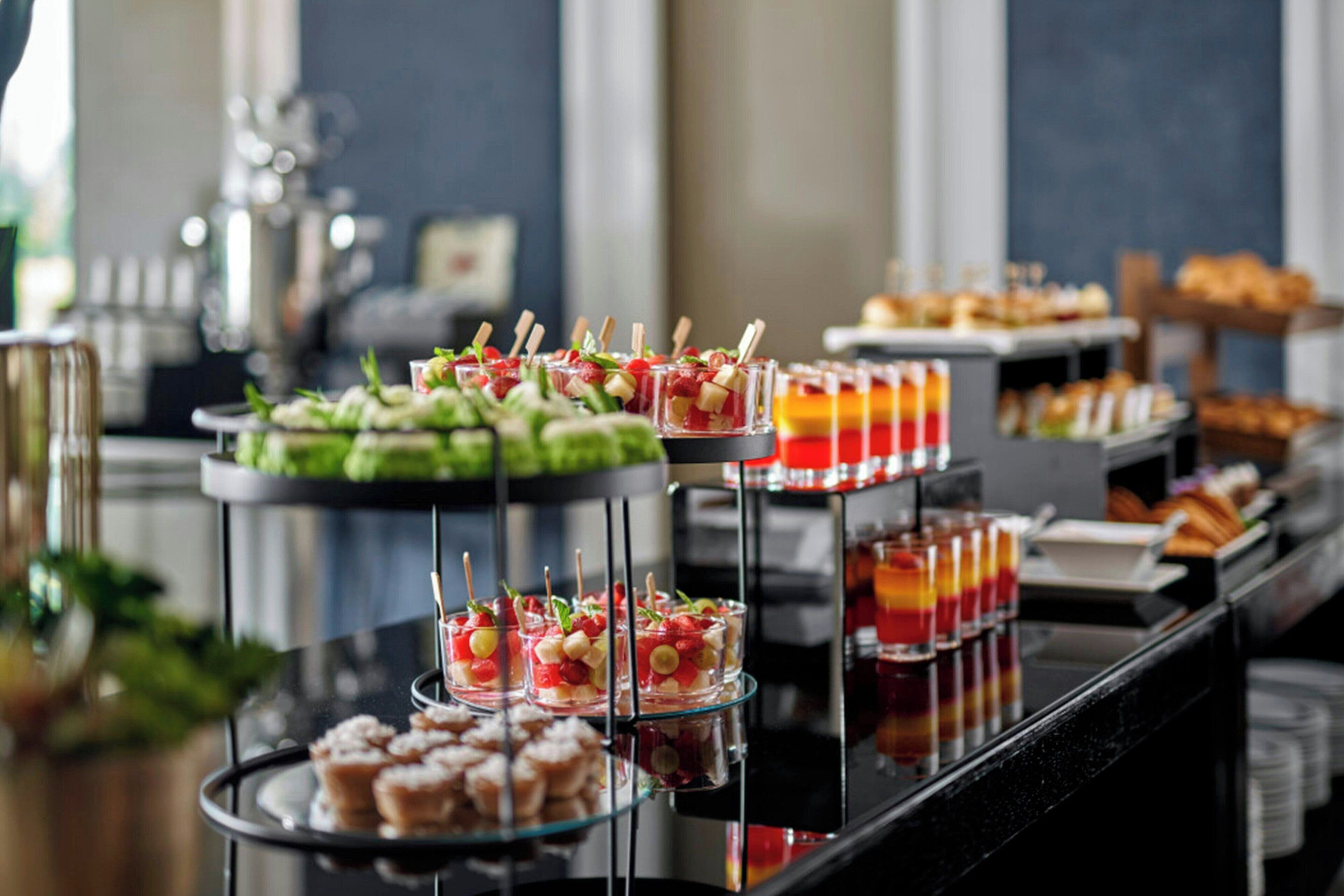 A buffet with various food items including fruit, pastries, and drinks.