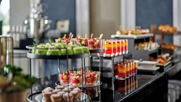 A buffet with various food items including fruit, pastries, and drinks.