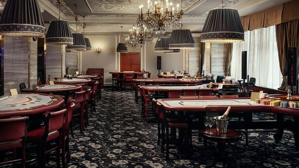 Un comedor formal con varias mesas, candelabros elegantes y una alfombra estampada.