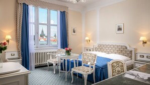 Habitación de hotel con cama, una mesa redonda con sillas, un escritorio y vista a un edificio a través del ventanal.