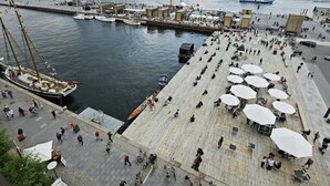 A waterfront promenade with boats docked, outdoor seating, and a modern building in the background. - Scandic Front (Copenhagen)