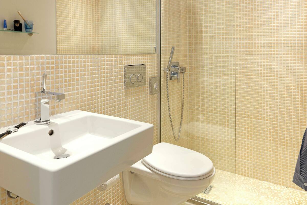 A bathroom with a white sink, toilet, and glass shower enclosure.