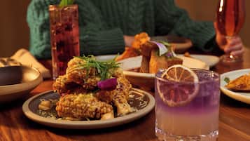 A dining table with various dishes, a tall glass of a purple drink, and a person in a green sweater.