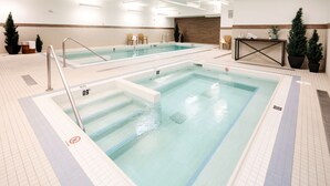Une piscine intérieure à l’eau claire, avec des couloirs délimités et un panneau indiquant qu’il est interdit de plonger.