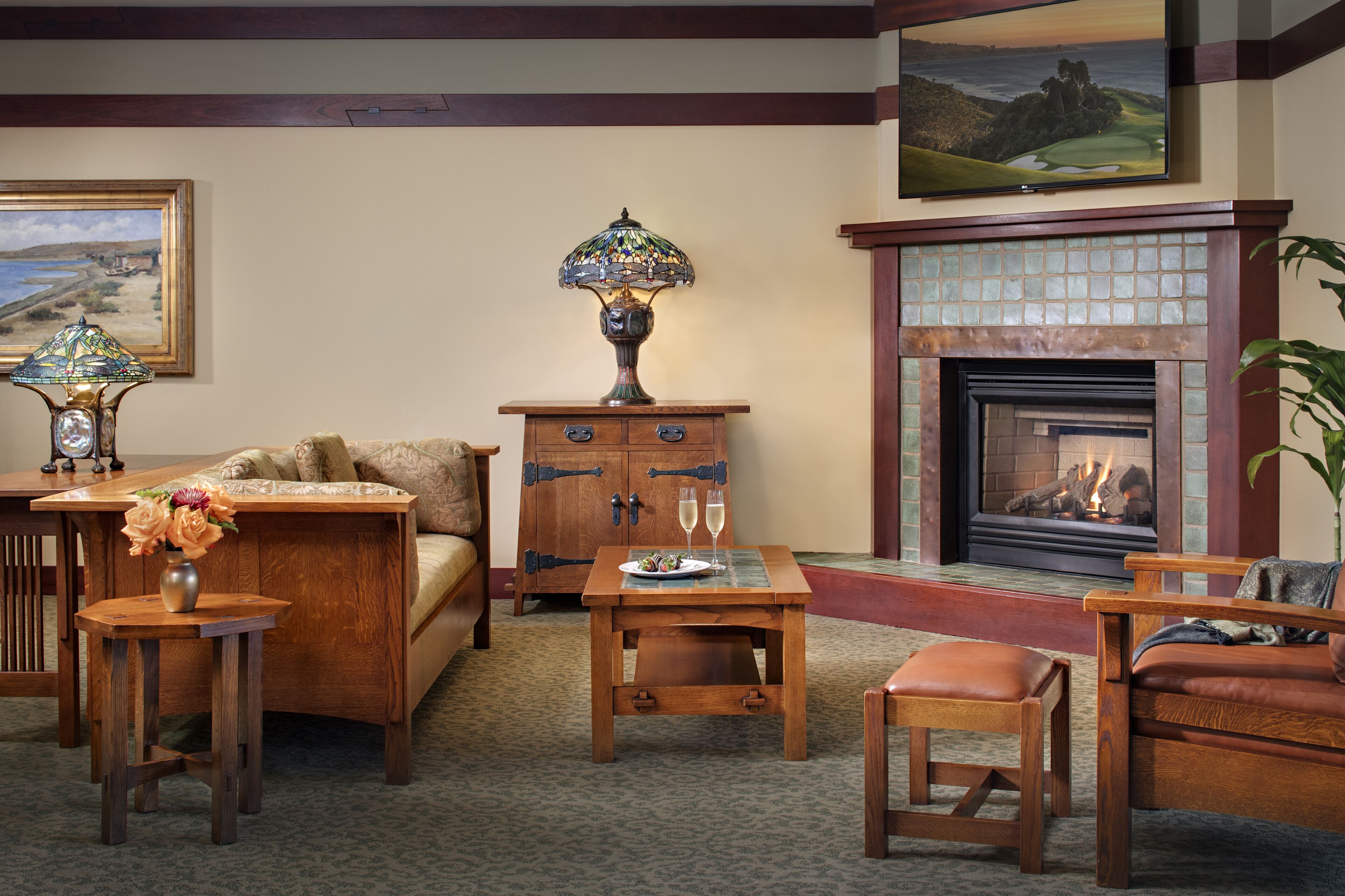 A cozy living room with a fireplace, wooden furniture, and a decorative lamp.