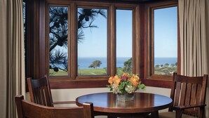 Un comedor con una mesa redonda, dos sillas de madera y un jarrón de flores.