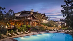 A resort with a swimming pool, lounge chairs, and a large building with multiple stories and balconies.