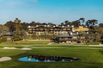 A conference room with multiple tables and chairs, large windows with a view of trees, and a chandelier. at The Lodge at Torrey Pines