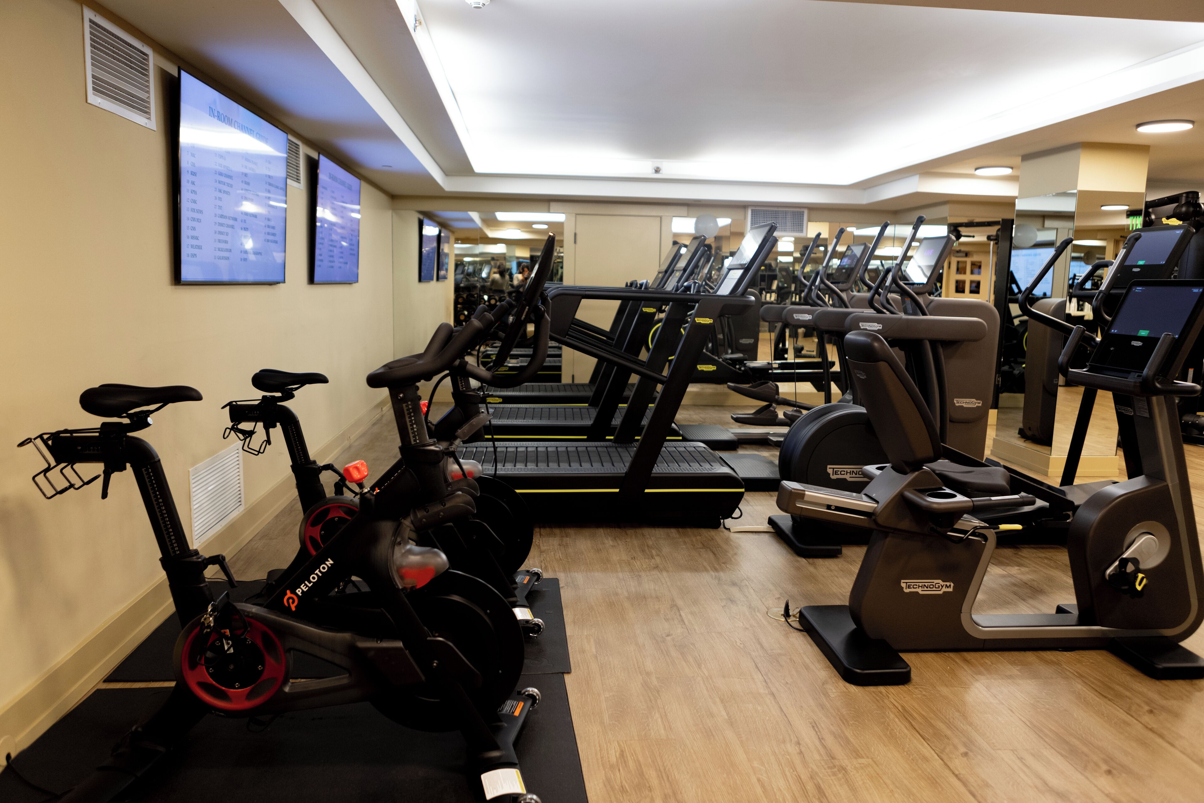 A gym with multiple treadmills, stationary bikes, and elliptical machines.