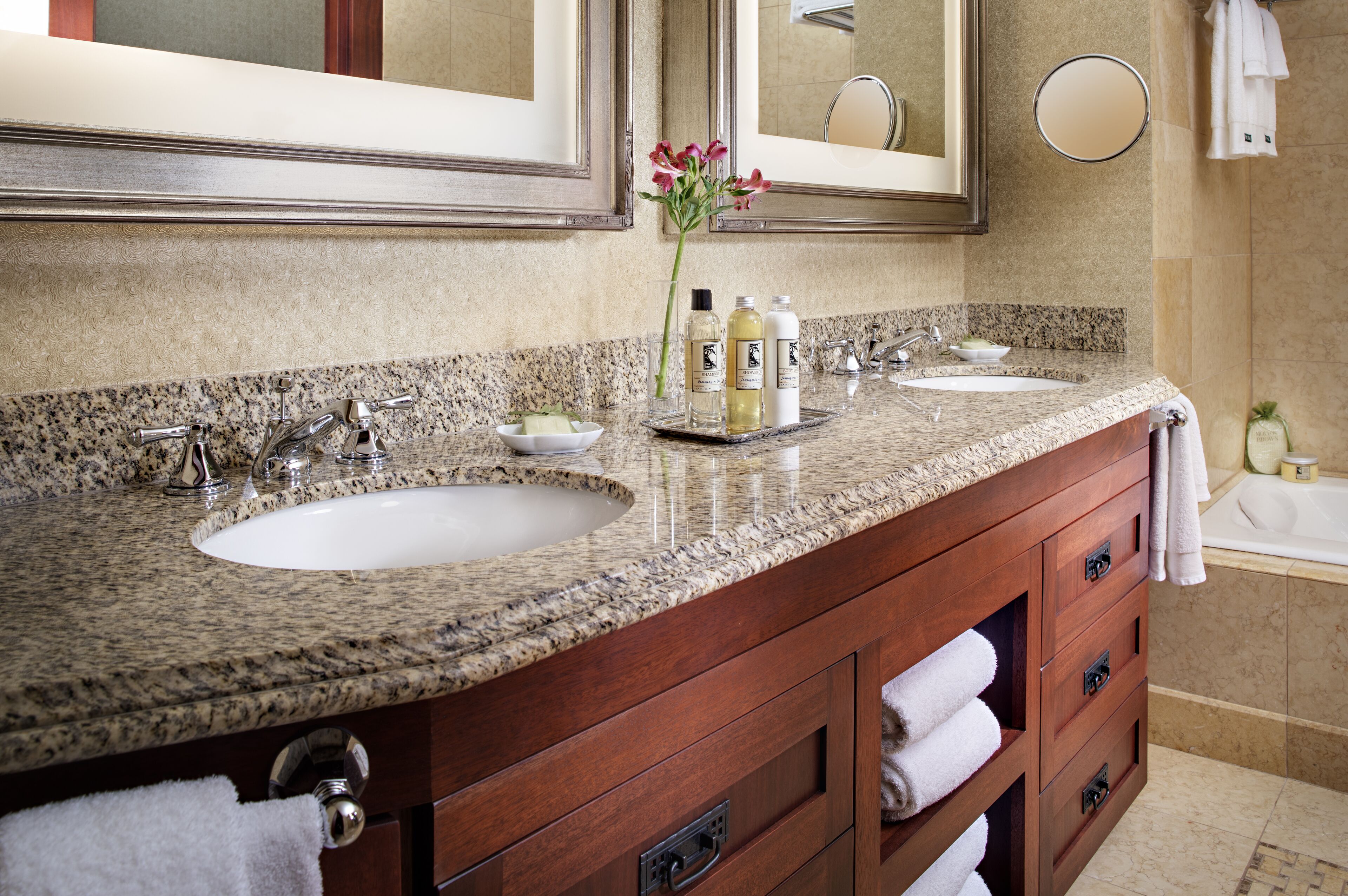 A bathroom with two sinks, a large mirror, and a wooden vanity with drawers.