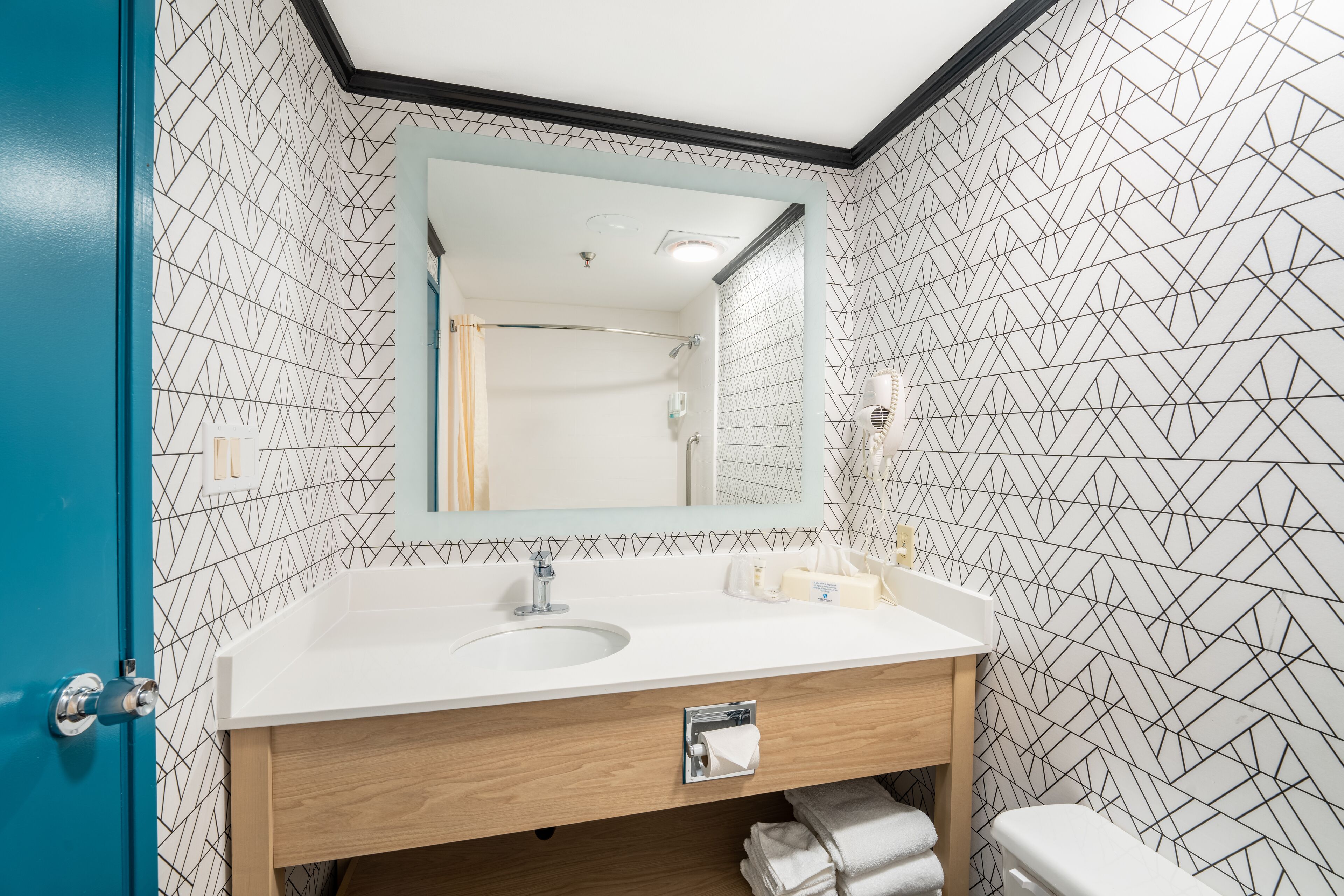Un bagno con lavandino bianco, mobile contenitore in legno e uno specchio grande.