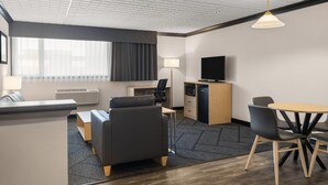 A modern hotel room with a sofa, desk, and dining area. - Sternwheeler Hotel & Conference Centre, Trademark by Wyndham (Whitehorse)