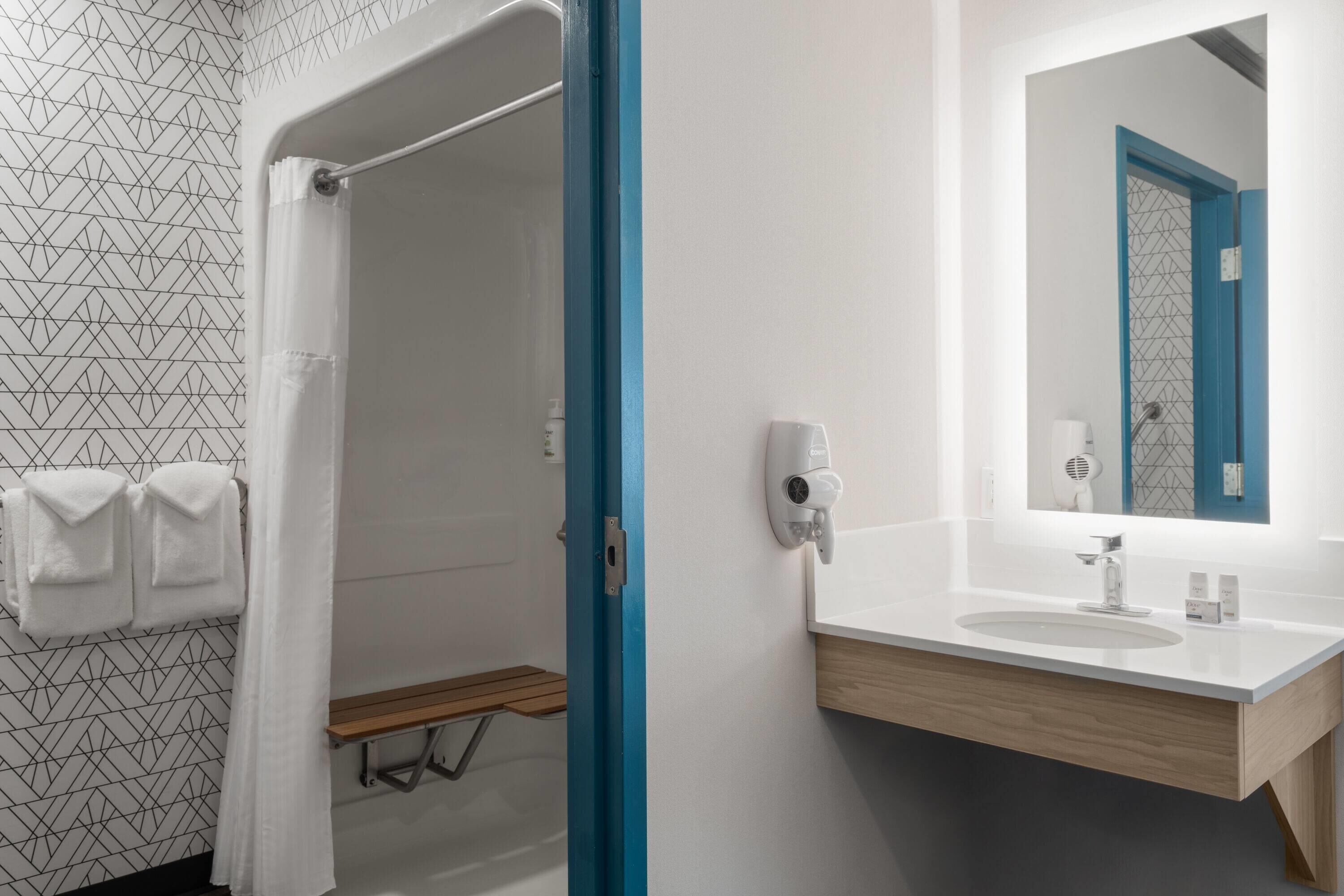 Ein Badezimmer mit Dusche, Waschbecken und Spiegel.