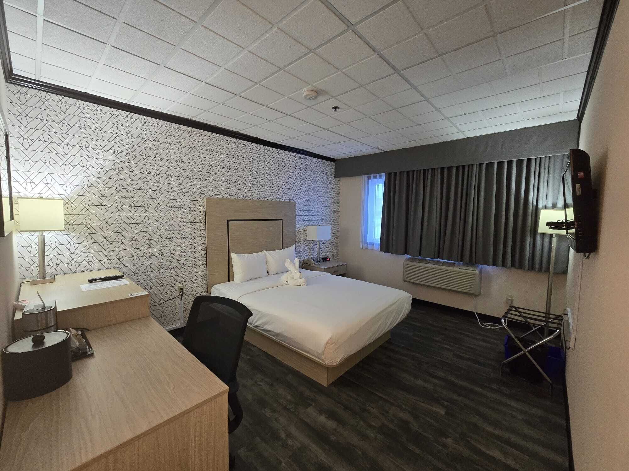 Een hotelkamer met een bed, bureau, stoel en televisie.