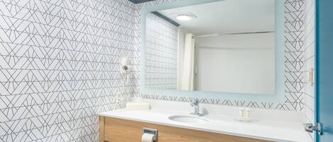 A modern bathroom with a white toilet, a sink with a mirror above it, and a shower area.