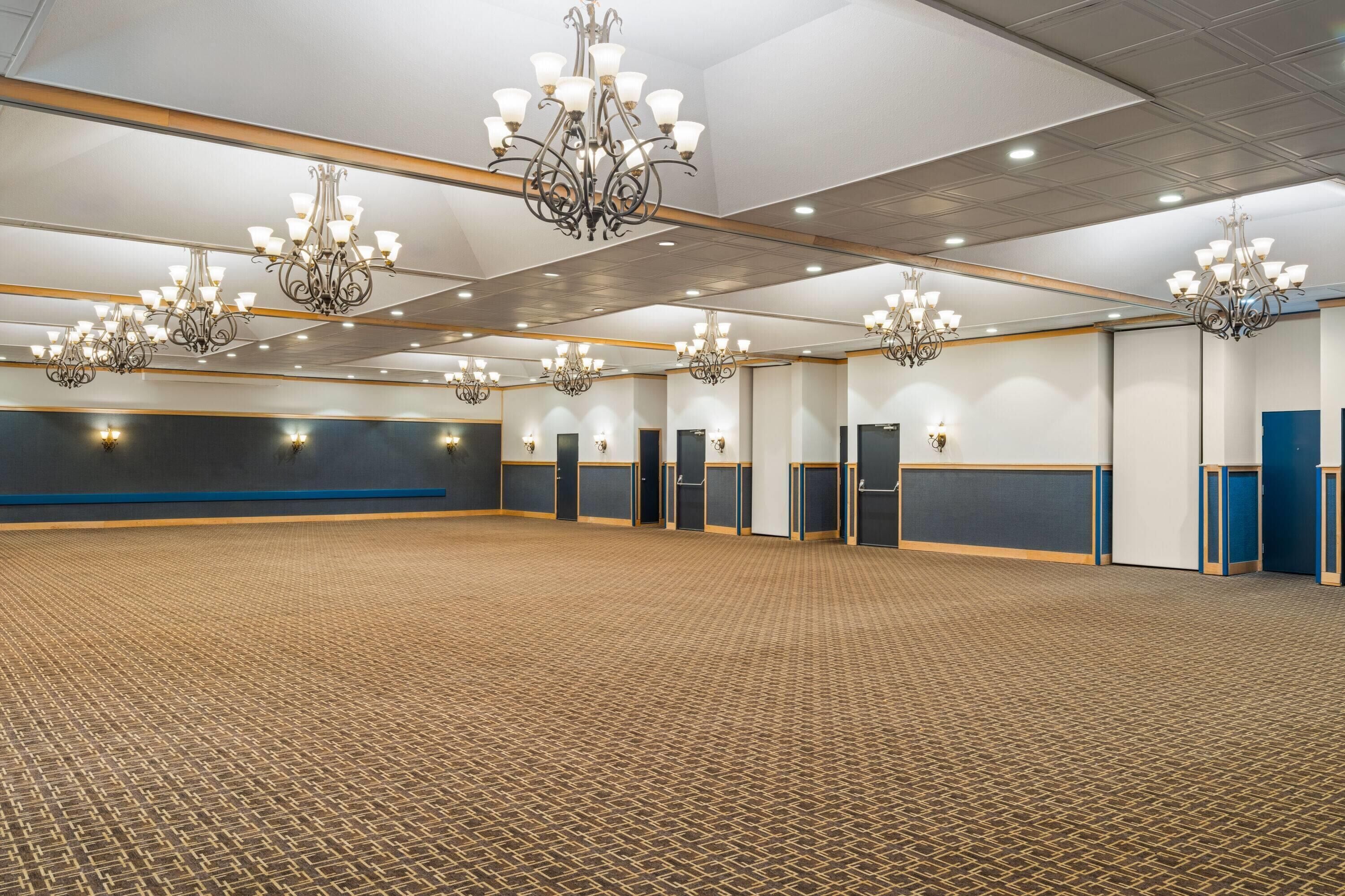 A large conference room with multiple chandeliers, a patterned carpet, and a blue accent wall.
