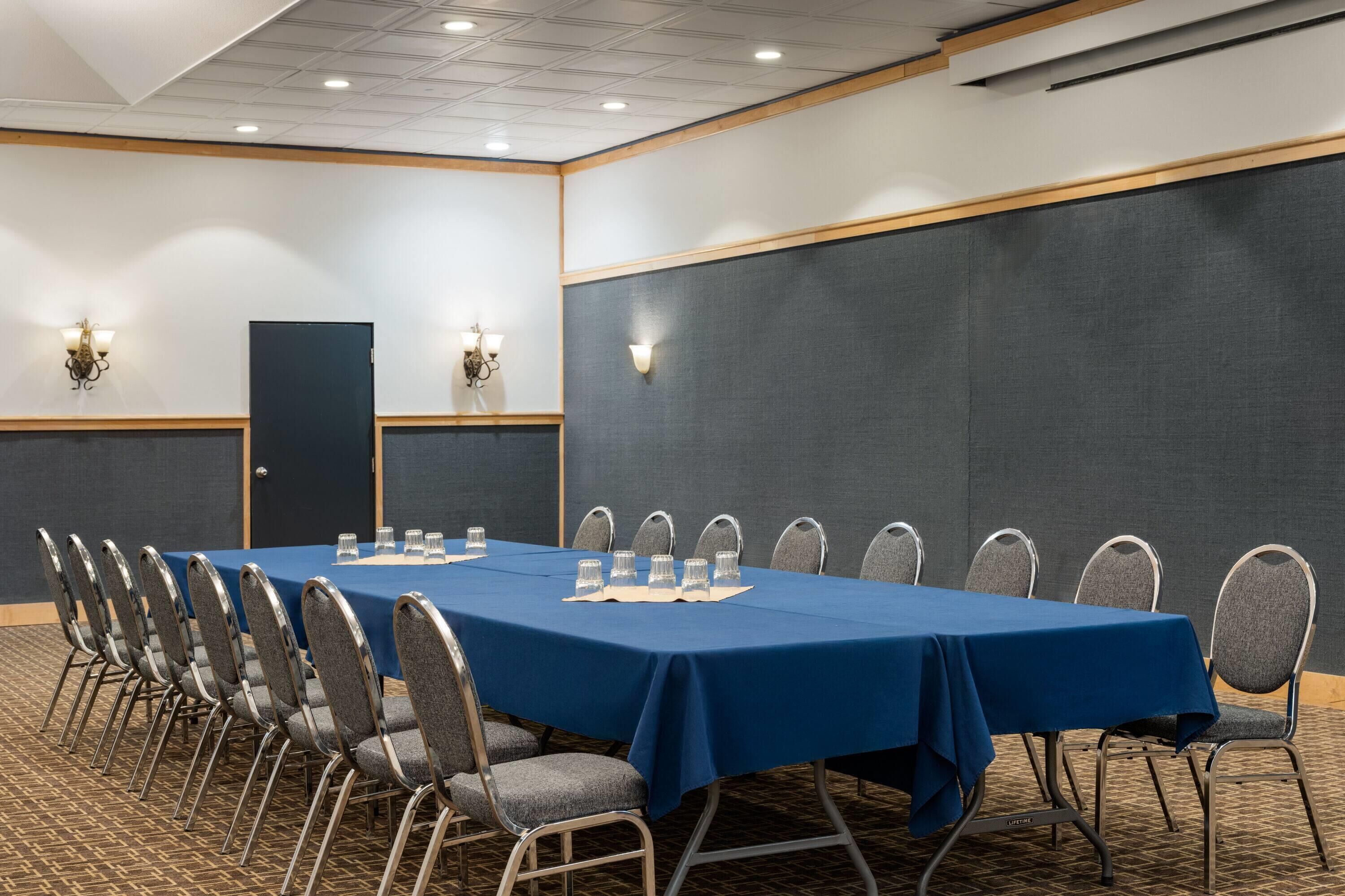 Una sala de conferencias con una larga mesa, sillas e iluminación en la pared.
