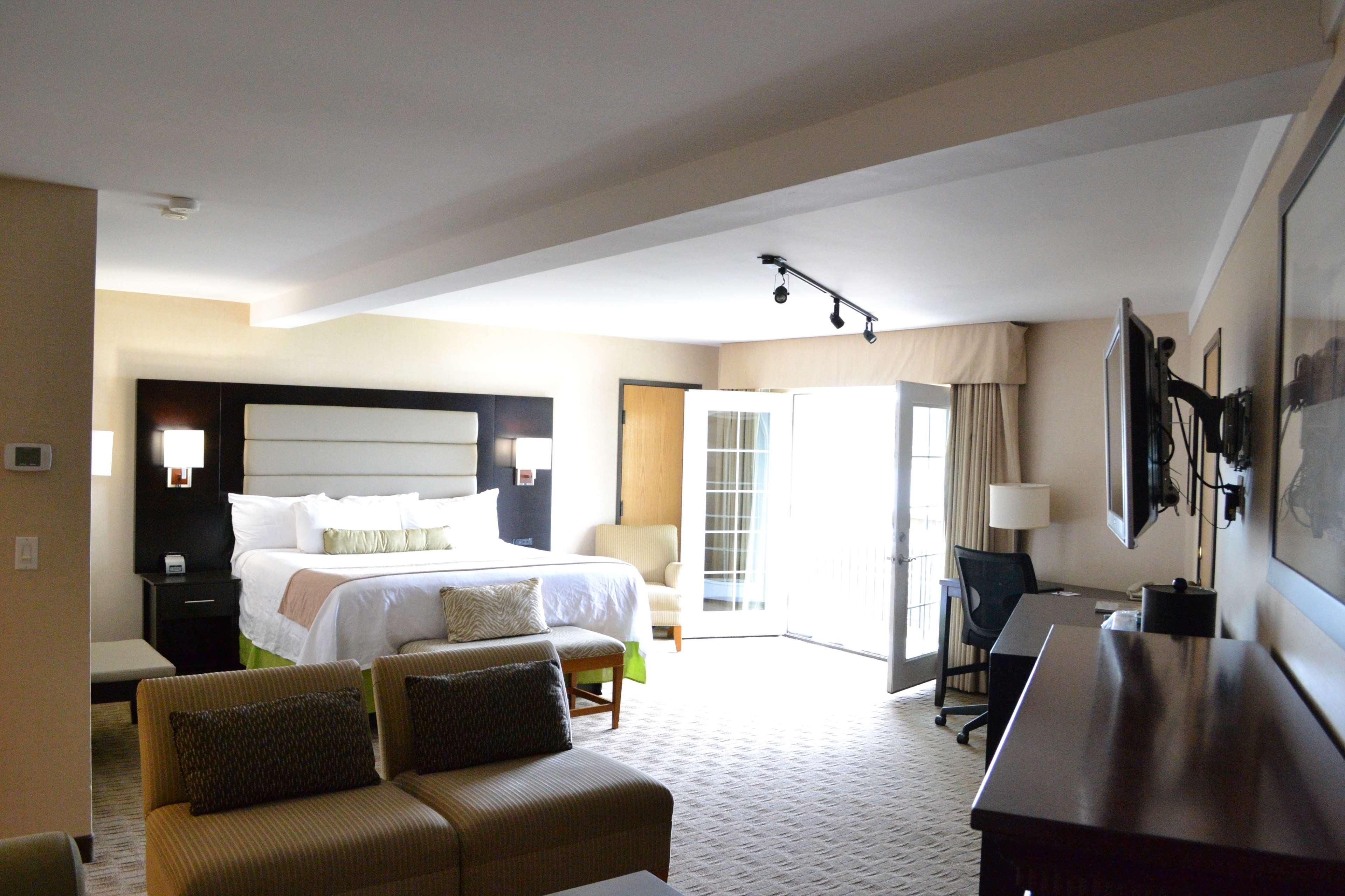 A hotel room with a large bed, a desk, a chair, and a sofa.