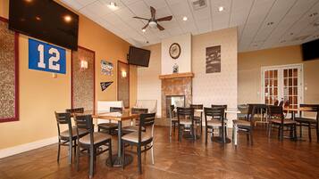 A restaurant with multiple tables and chairs, a ceiling fan, and a fireplace.