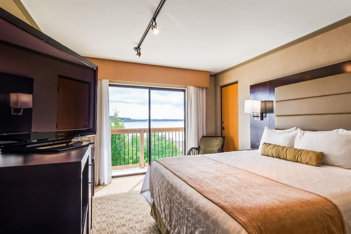 Hotelkamer met een groot bed, televisie, bureau en balkon met uitzicht op het water.