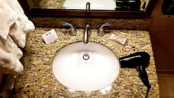 A bathroom sink with a towel, a hairdryer, and a card on the countertop.