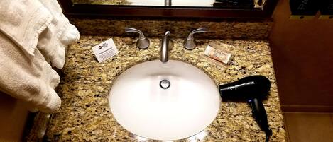 A bathroom sink with a towel, a hairdryer, and a card on the countertop.