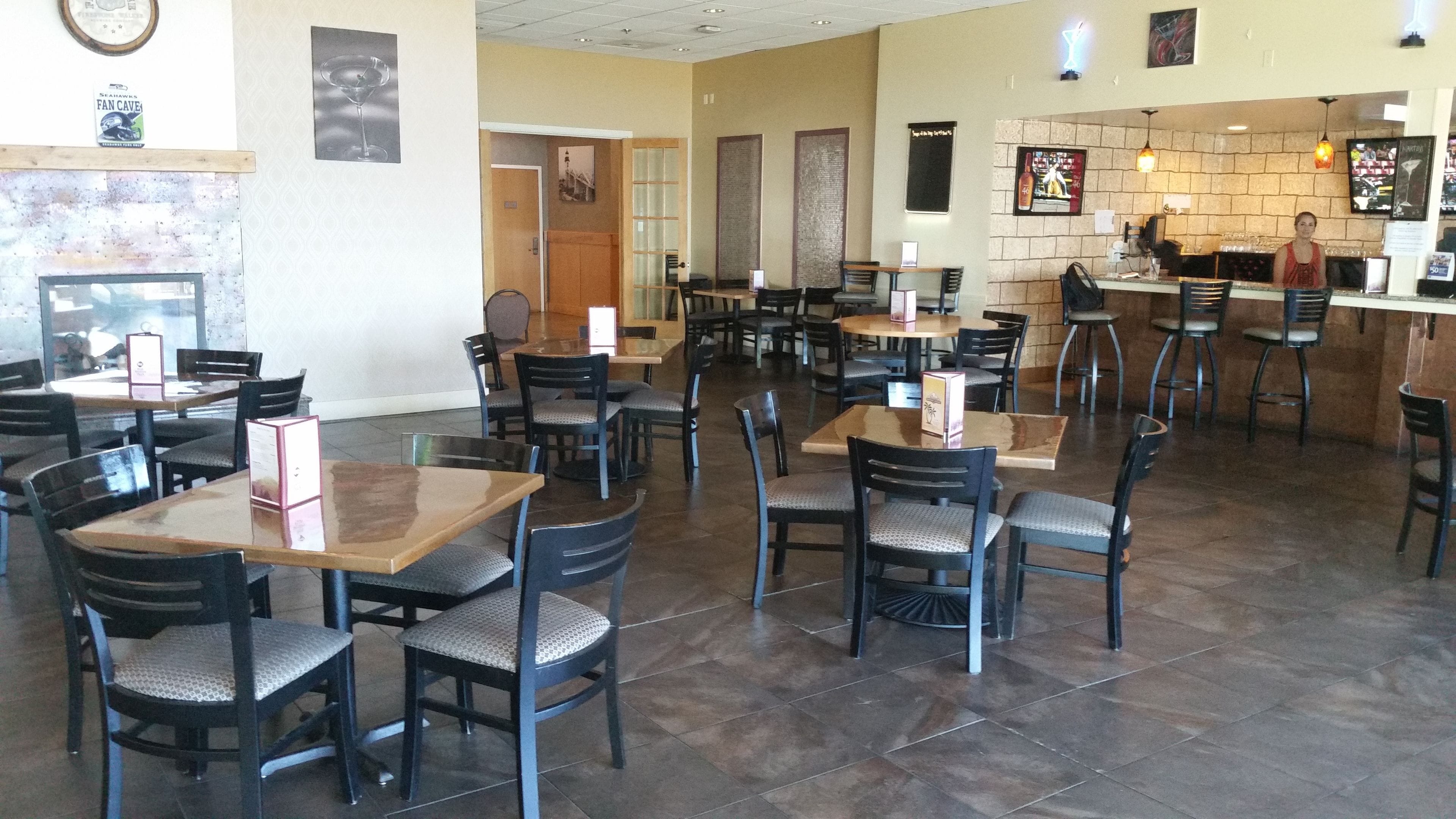 A restaurant with multiple tables and chairs, a bar area, and a counter.