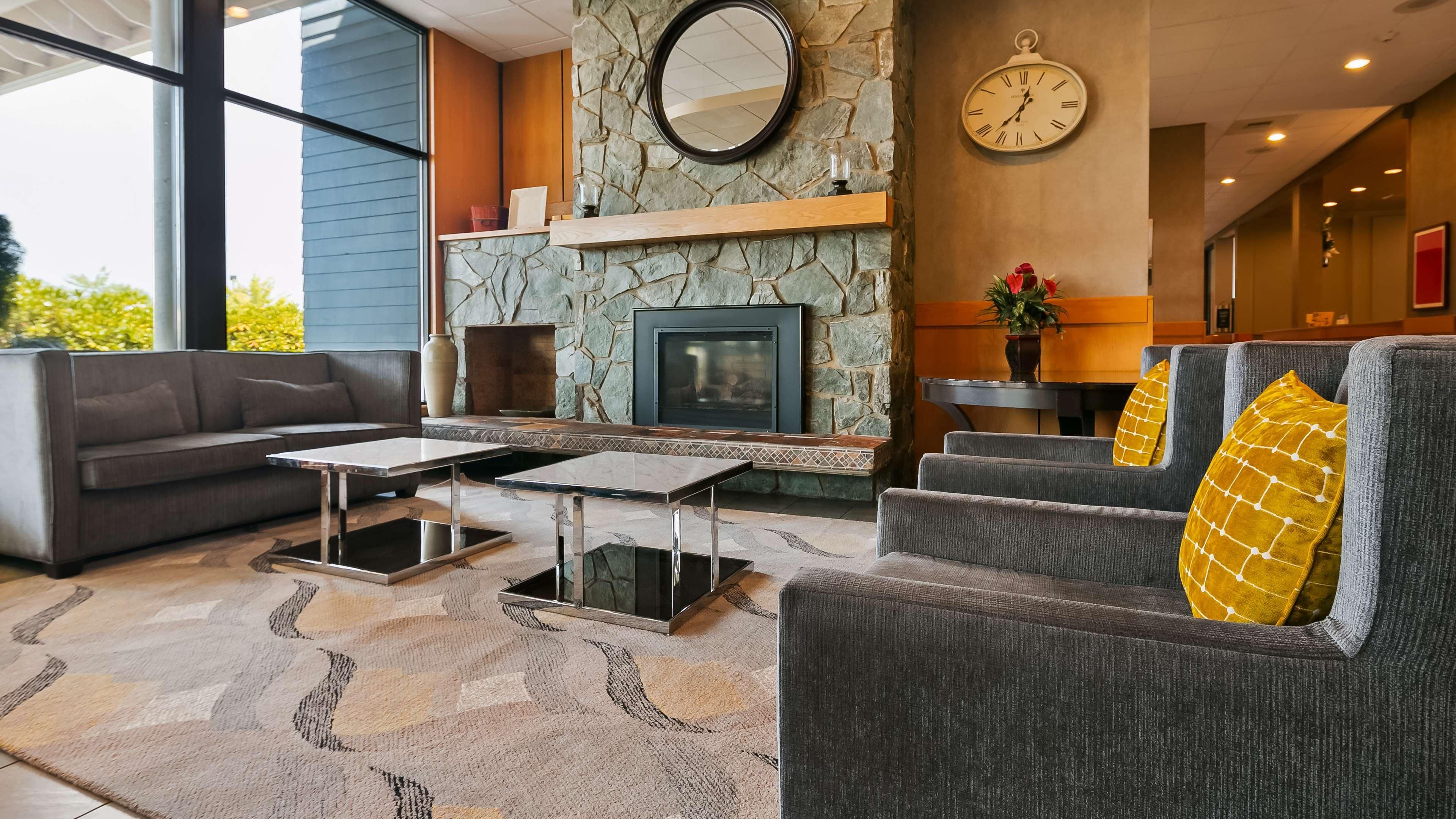 A modern living room with a stone fireplace, a sofa, a coffee table, and a clock on the wall.