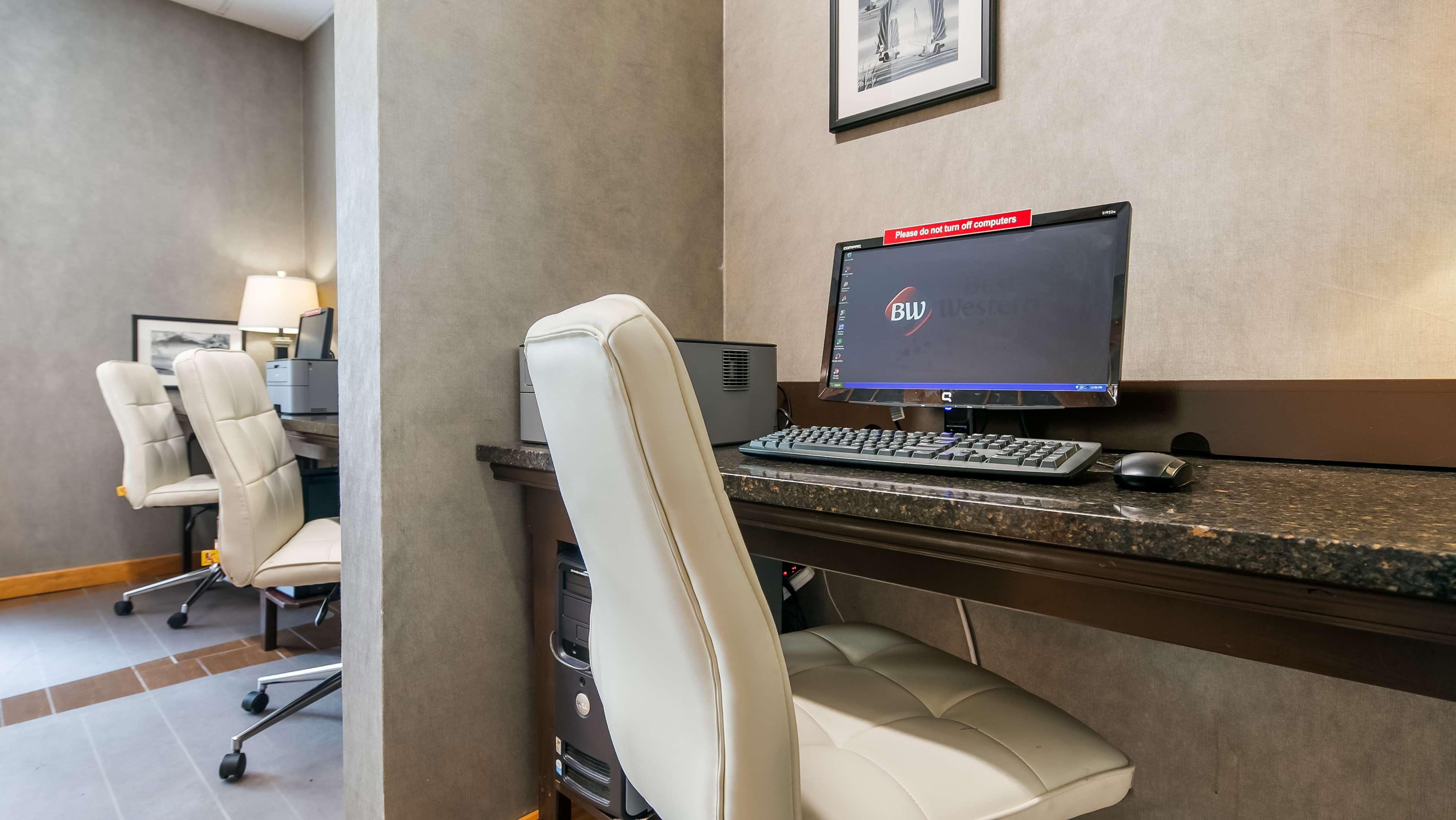 A hotel office with a desktop computer, a keyboard, a mouse, and a chair.
