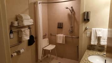 Une salle de bain avec une douche, des toilettes et un lavabo. Des serviettes et des articles de toilette sont disposés sur des étagères.