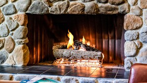 A stone fireplace with a fire, a book titled "Aviation History," and a clock on the mantel.