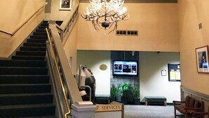 A staircase with a handrail, a chandelier, and a sign labeled "SERVICES".