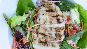 A plate with grilled chicken and a mixed green salad.