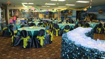 A banquet hall with round tables, chairs, and a decorative backdrop.