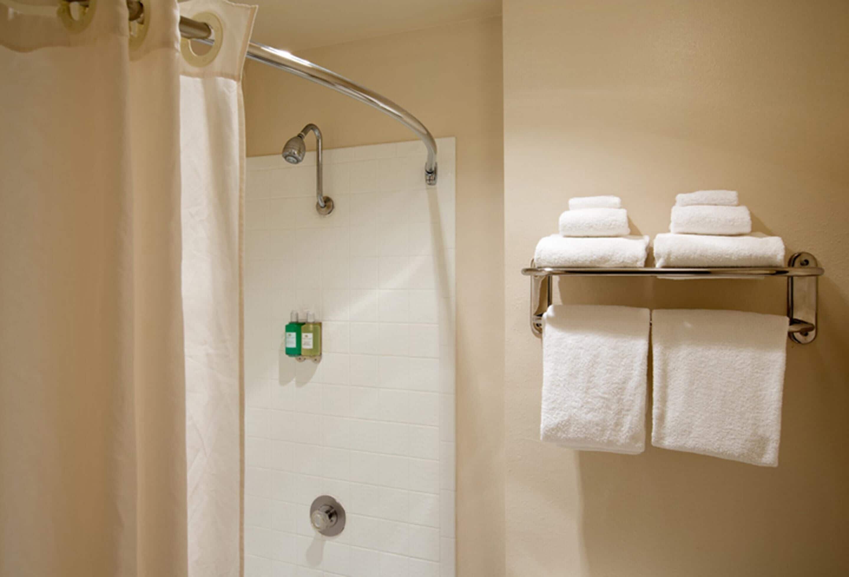 Una ducha con puerta de vidrio, un perchero con toallas dobladas y un panel de control de la ducha.