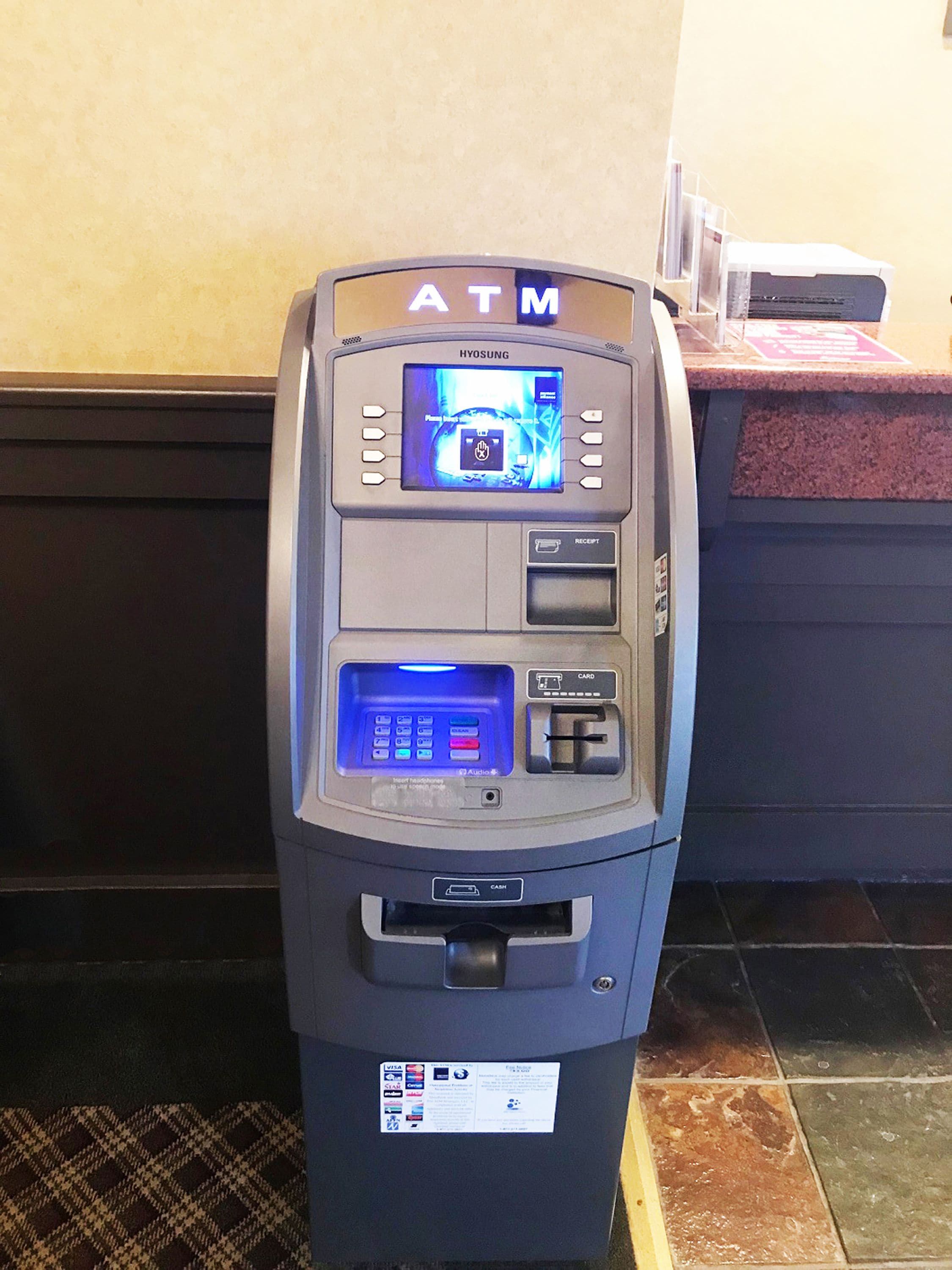 An ATM machine with a screen displaying a transaction interface, a card slot, and a cash dispenser.