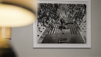 Ett inramat svartvitt fotografi som föreställer en byggnad med en staty och träd.