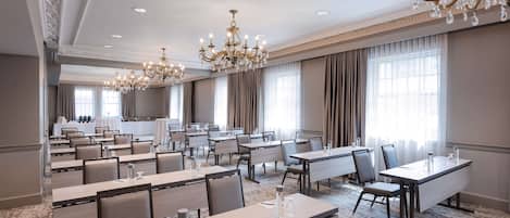 A conference room with multiple tables, chairs, and a chandelier.