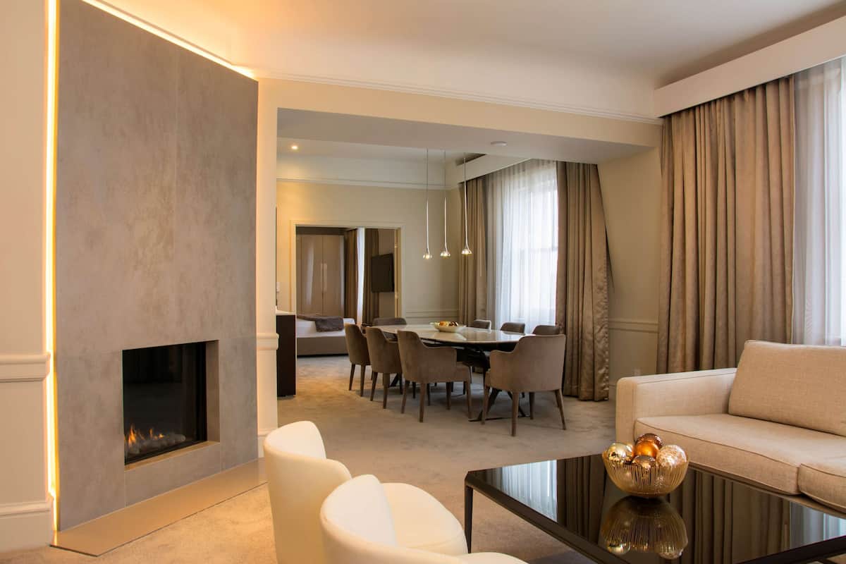 A modern living room with a fireplace, a dining area with a round table and chairs, and a sofa.