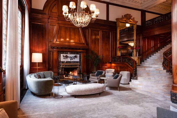 A grand lobby with a fireplace, elegant furniture, and a staircase.