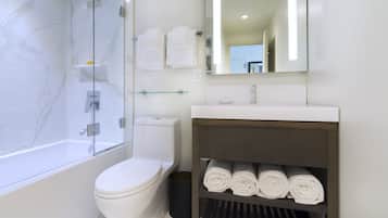 A modern bathroom with a glass-enclosed shower, a white toilet, a sink with a wooden vanity, and a mirror above the vanity.