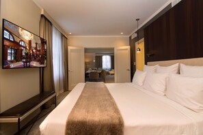 A hotel room with a large bed, a mirror, a desk, and a view of the hotel's lobby.